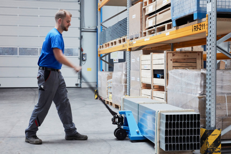 man moves blue pallet truck into storage