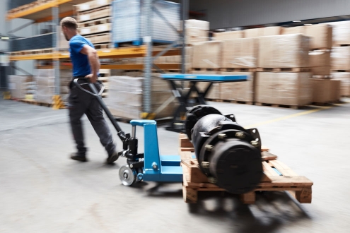 man pushes blue pallet truck into storage