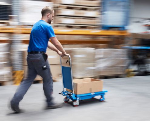 man moves blue lift table into stock