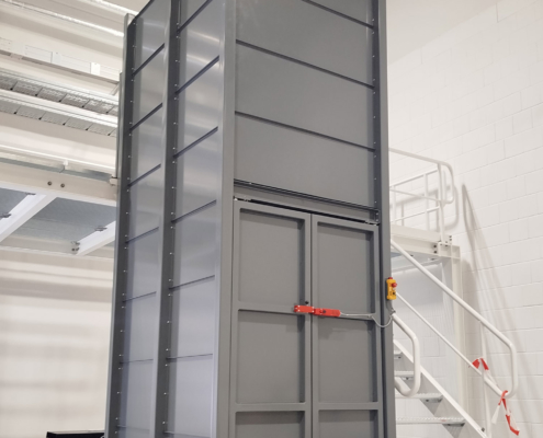 Individuell gefertigter Hubtisch mit offener Einhausung zur Integration in eine bestehende Grube Mehrfach-Scherenhubtisch mit geschlossener Einhausung in industrieller Produktionsumgebung. Die Einhausung ist nach oben offen und steht auf einem sensiblen Boden mit Fußbodenheizung.