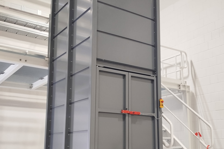Individuell gefertigter Hubtisch mit offener Einhausung zur Integration in eine bestehende Grube Mehrfach-Scherenhubtisch mit geschlossener Einhausung in industrieller Produktionsumgebung. Die Einhausung ist nach oben offen und steht auf einem sensiblen Boden mit Fußbodenheizung.